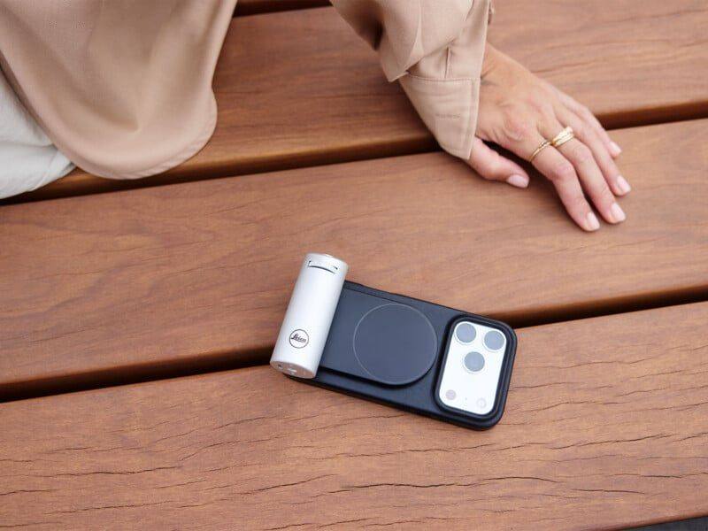 The Leica LUX grip in its new silver finish, attached to an iPhone via MagSafe. The grip is priced at $395 and includes a one-year LUX PRO subscription.